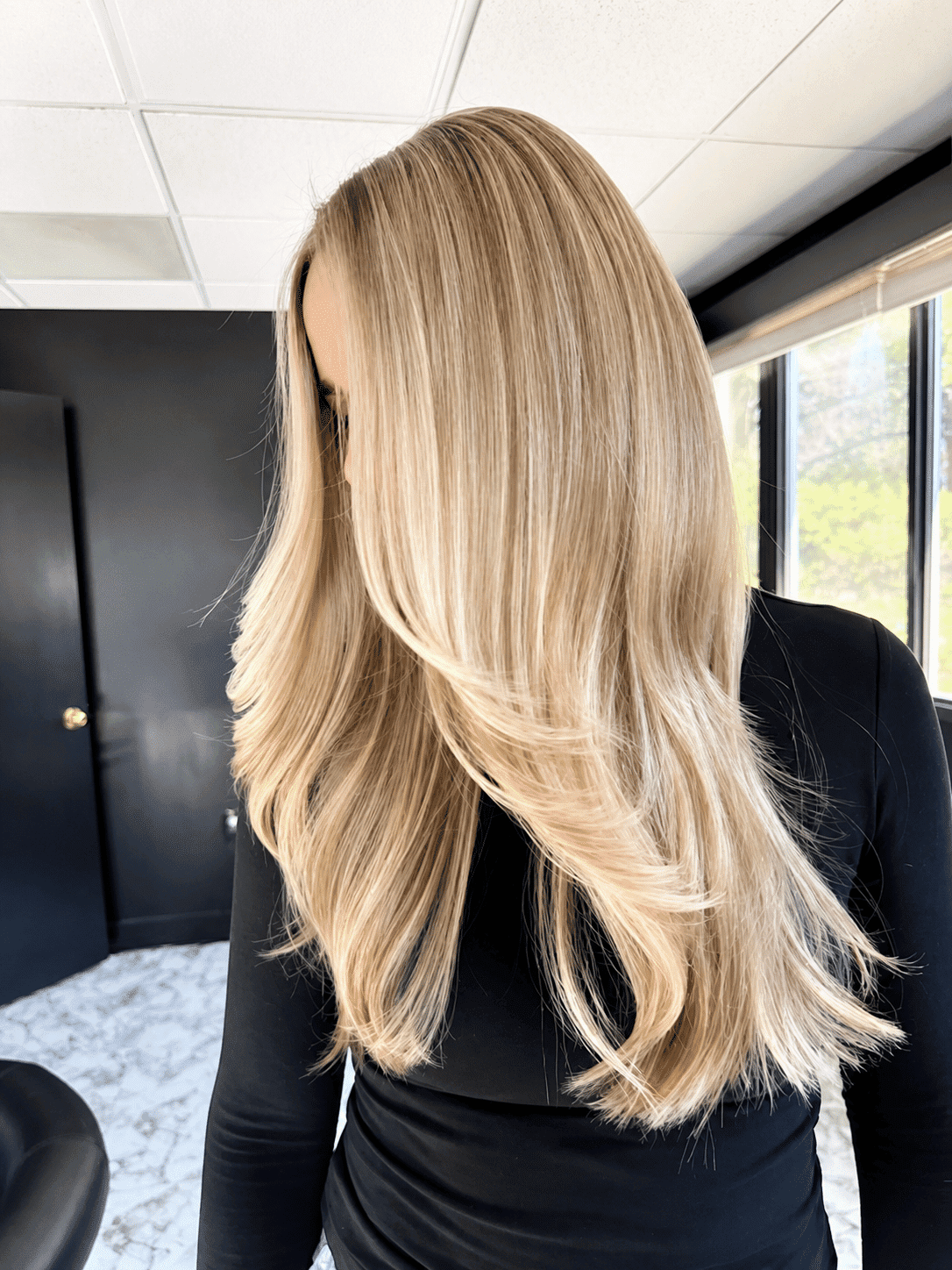 Long, flowing blonde hair with soft waves, styled in a modern salon setting.